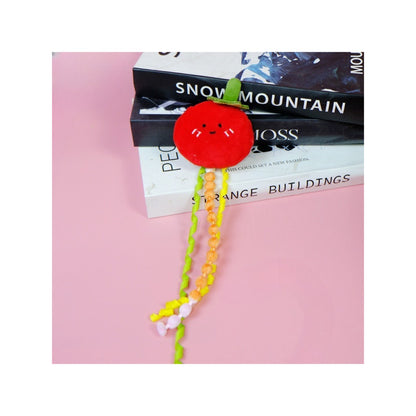 Moo fruit plush cat toy with ribbons placed next to a small plant
