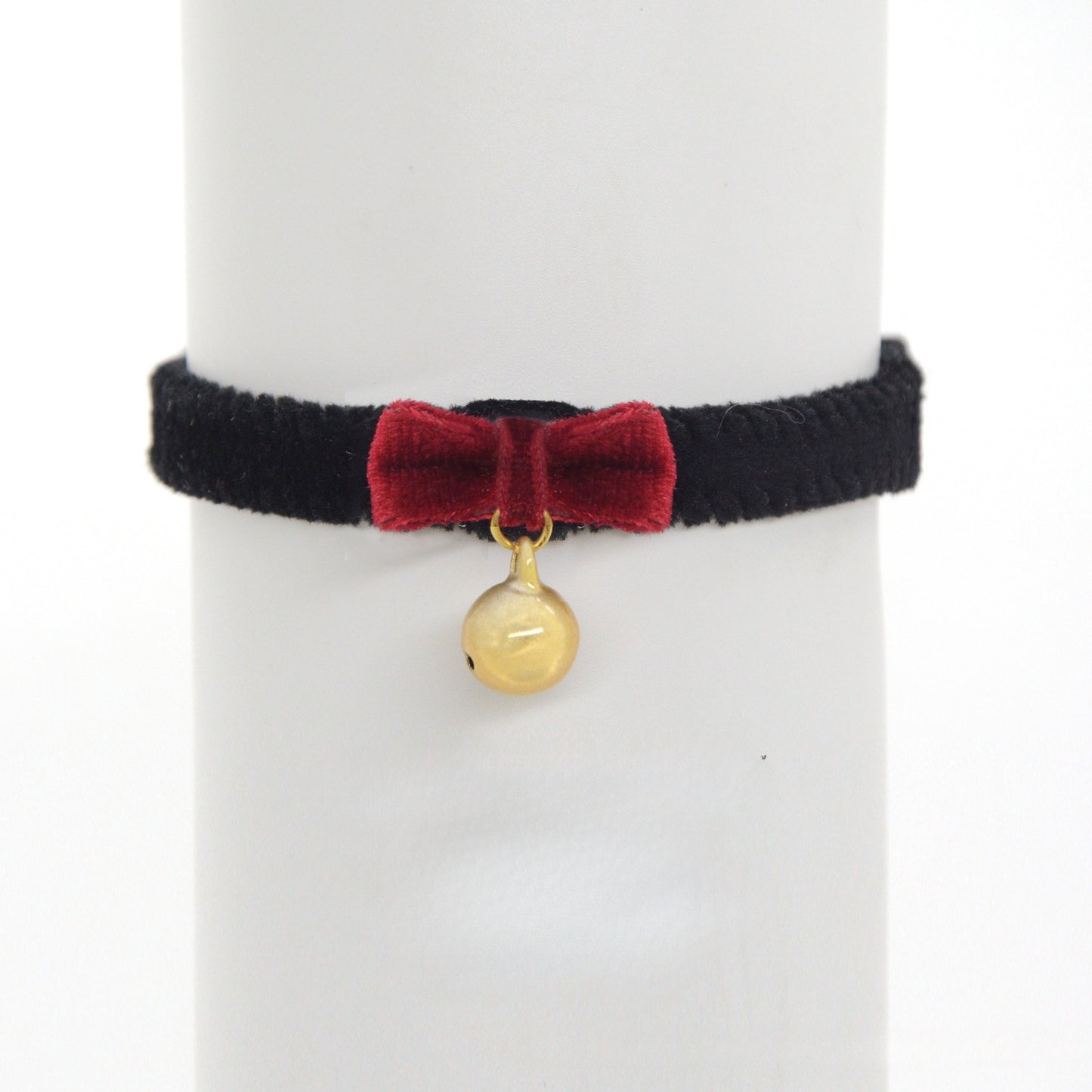 Close-up of black velvet cat collar showing adjustable strap and bell