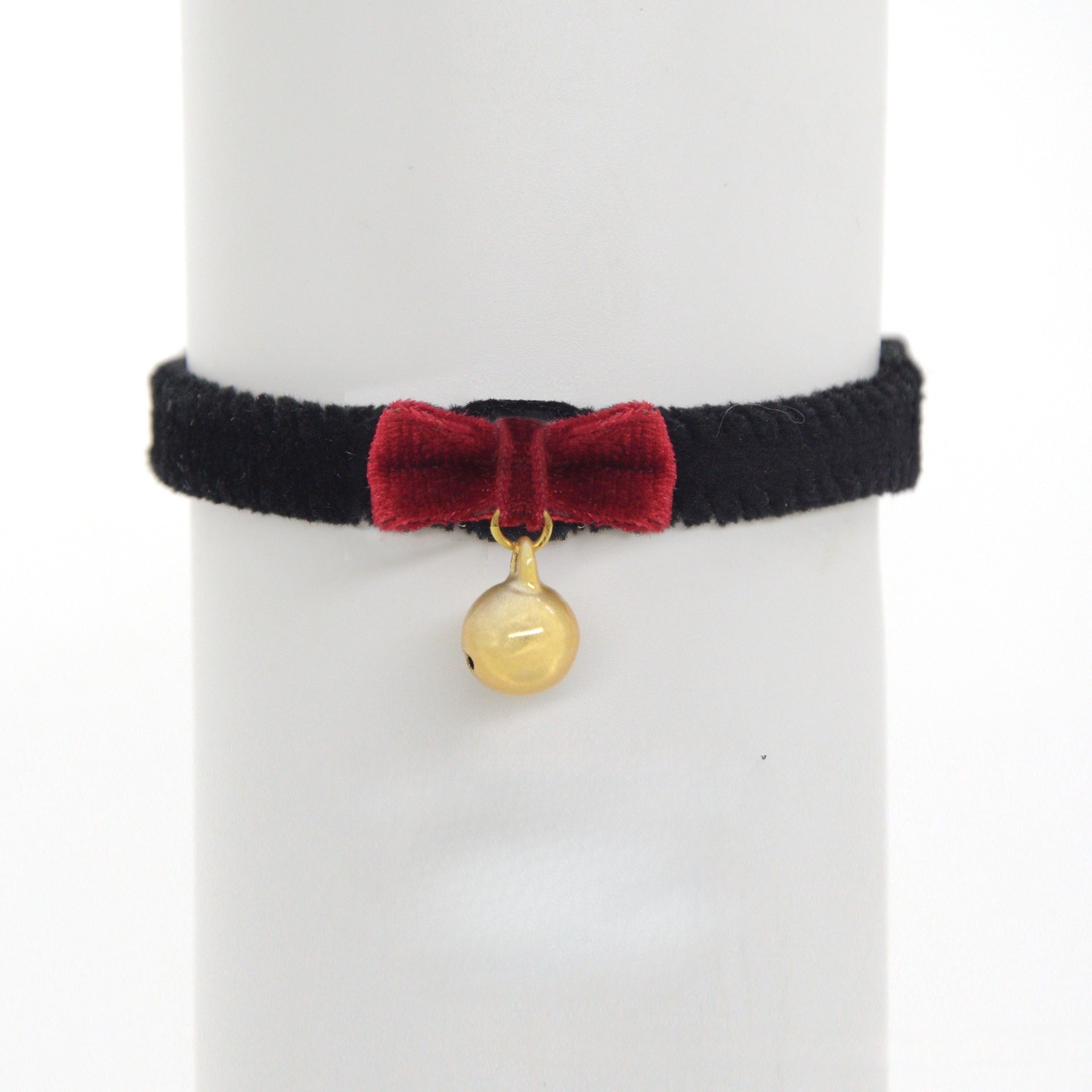 Close-up of black velvet cat collar showing adjustable strap and bell