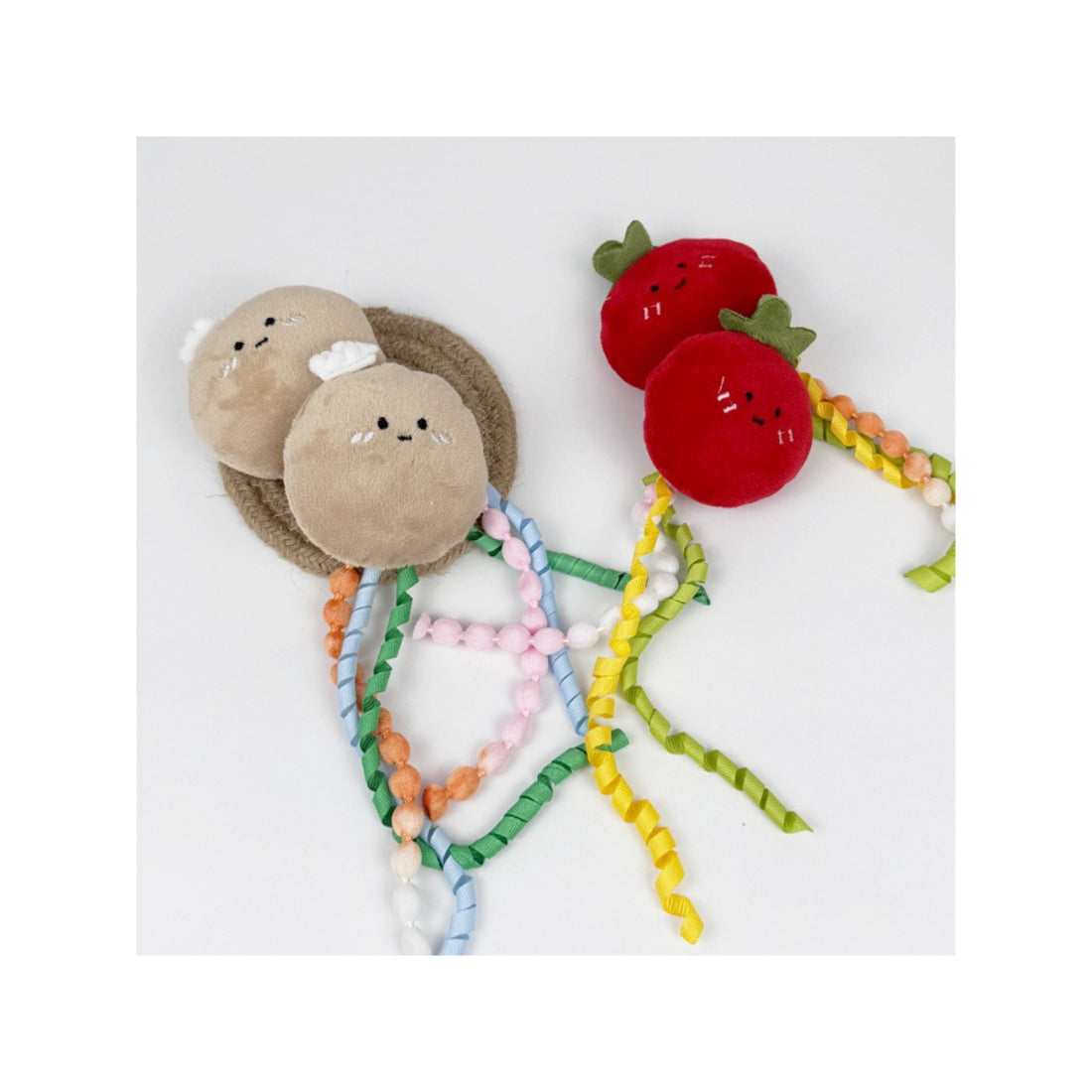 Moo fruit plush cat toy with ribbons displayed on a wooden surface