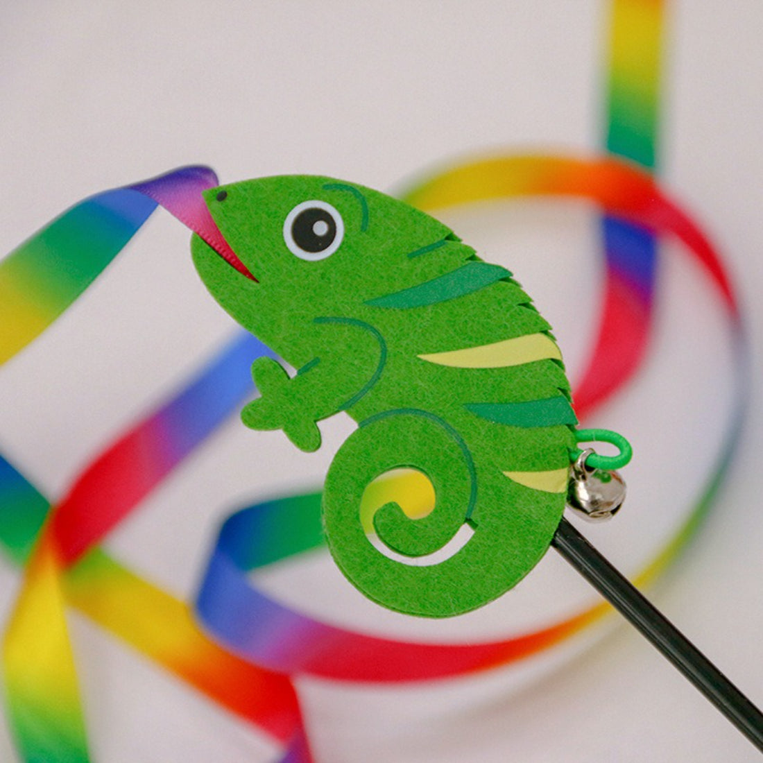 Cat playing with the colorful ribbon wand toy held by a person