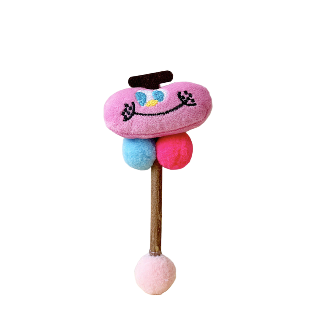 Pink Apple toy with a stitched smiling face, blue and pink balls, and a pale pink ball at the end of its stick.
