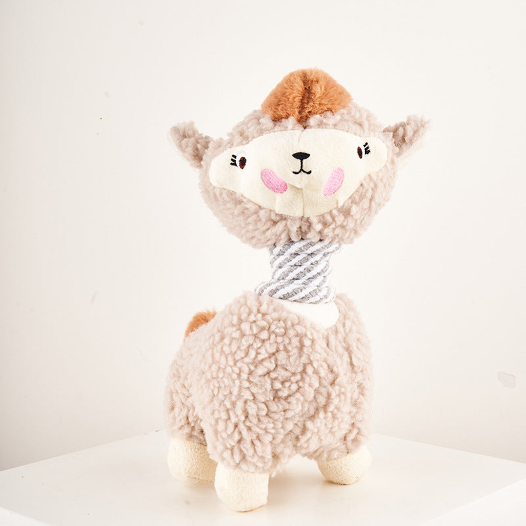 Beige alpaca dog toy standing on a white surface, front view.