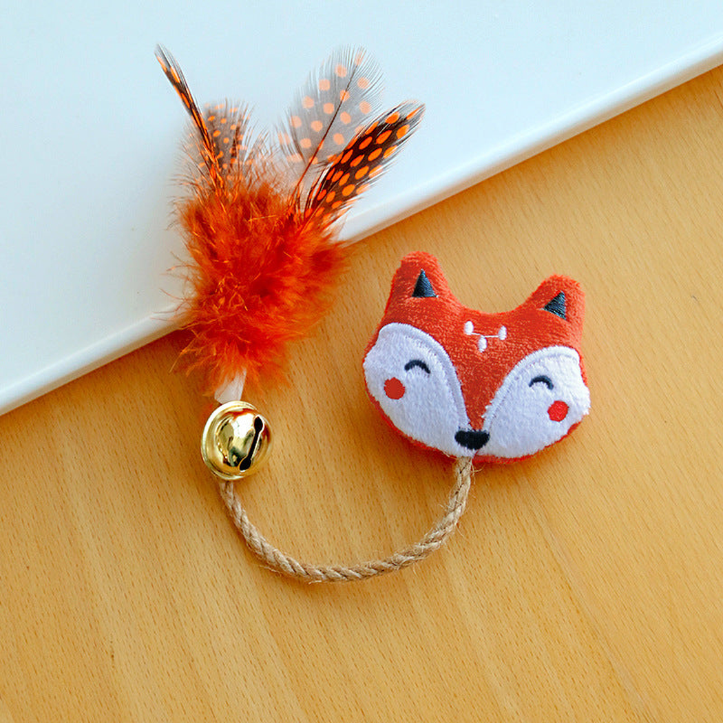 Fox cat toy with an embroidered face, braided cord, gold-colored bell and orange spotted feathers.