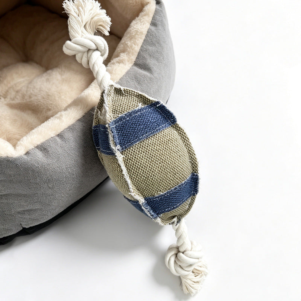 Beige and blue oval rope dog toy beside a plush pet bed