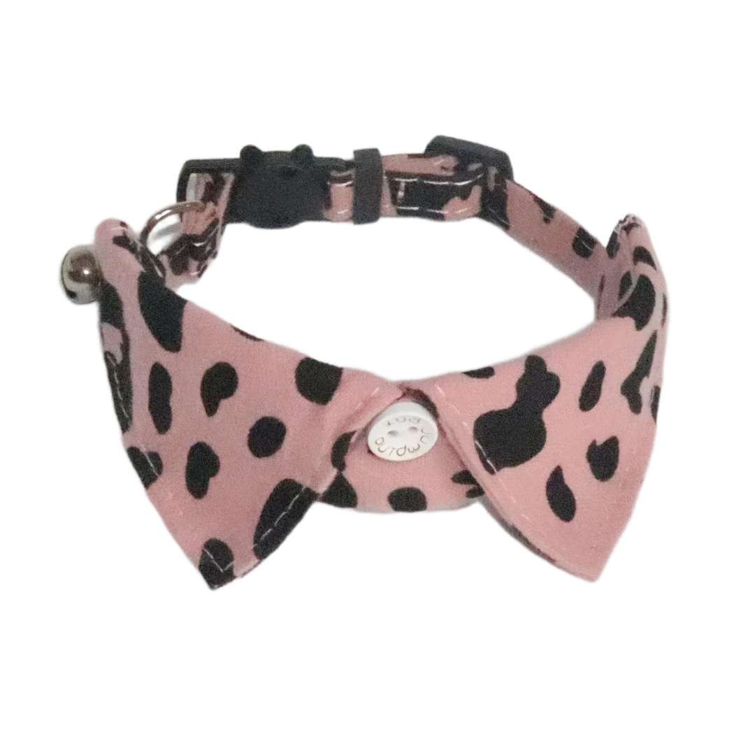 Dusty pink cow-print cat collar with black-spotted pointed panels and bell