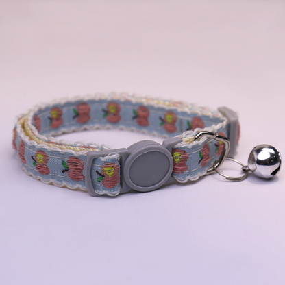 Light blue cat collar with pink apple pattern, gray buckle and bell