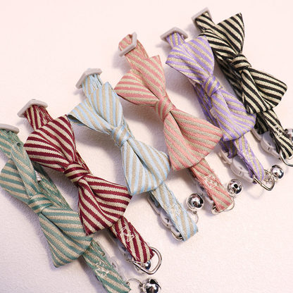 Six striped bow cat collars arranged diagonally with bells and buckles visible