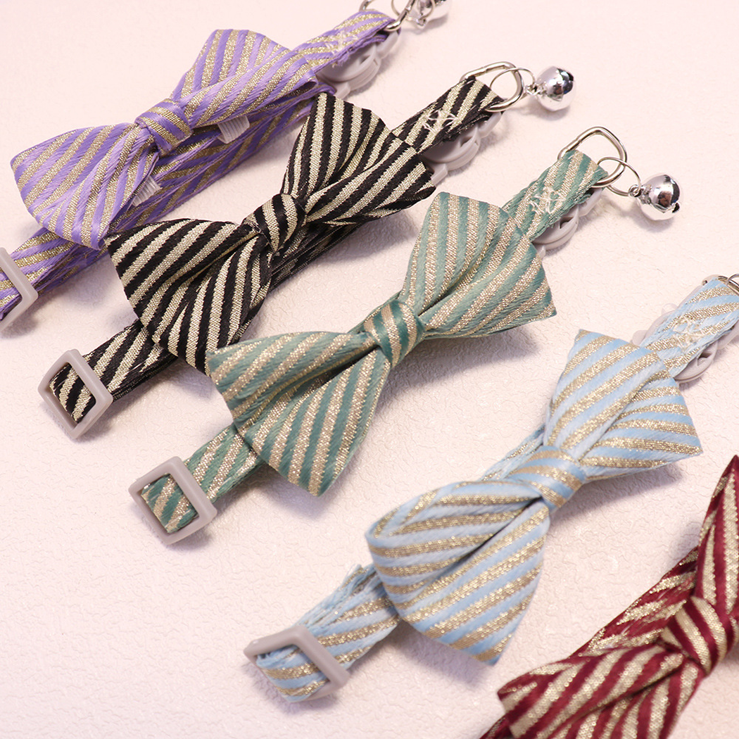 Close-up of striped bows, adjustment sliders, rings and bells on assorted cat collars