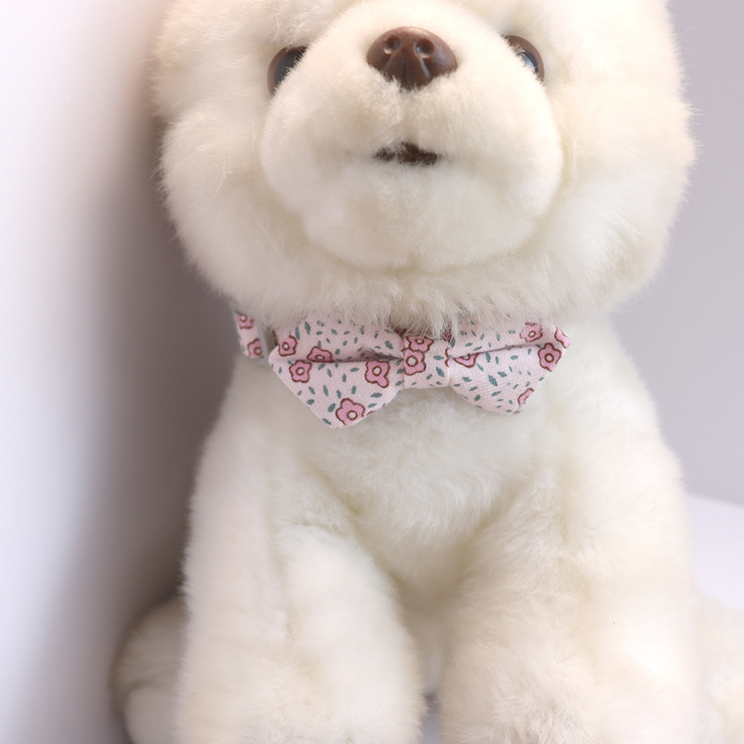 Light pink floral bow cat collar displayed on a plush animal model
