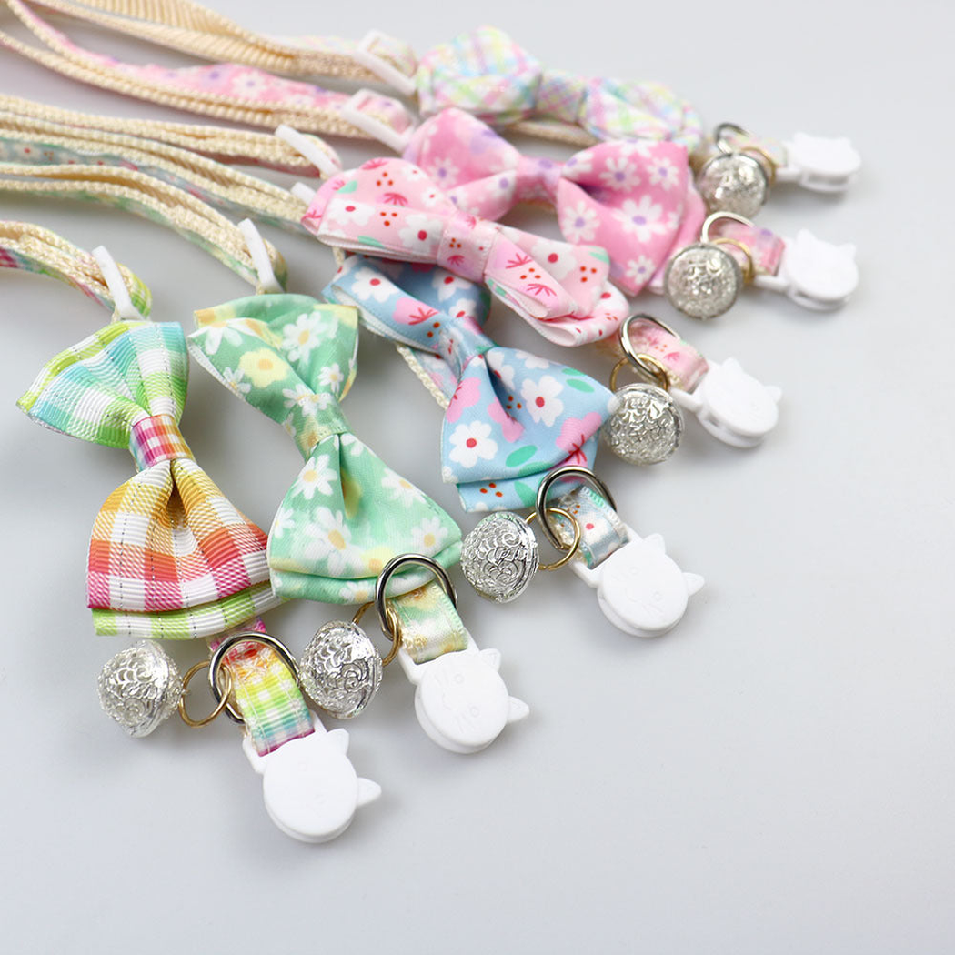 Close-up of patterned bows, bells and cat-face buckles on multiple collars