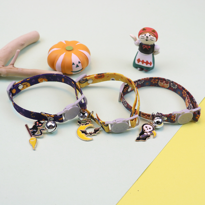 Three Halloween cat collars arranged with pumpkin and figurine decorations