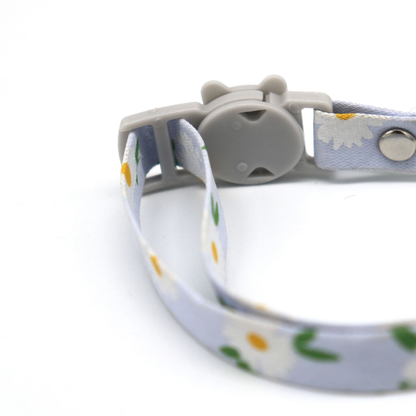 Close-up of the cat-face buckle and threaded daisy-print collar strap