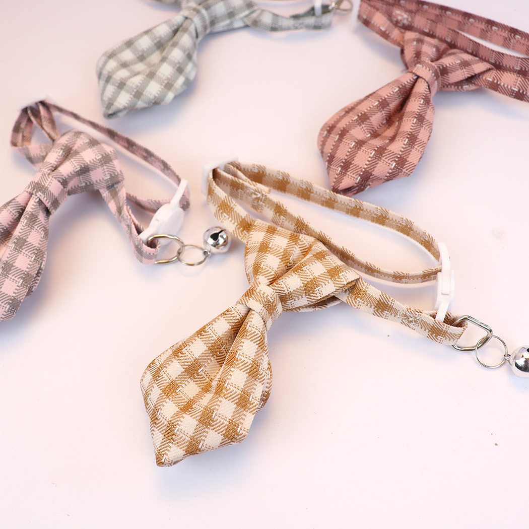 Close-up arrangement of plaid cat collars with adjustable straps, buckles and bells