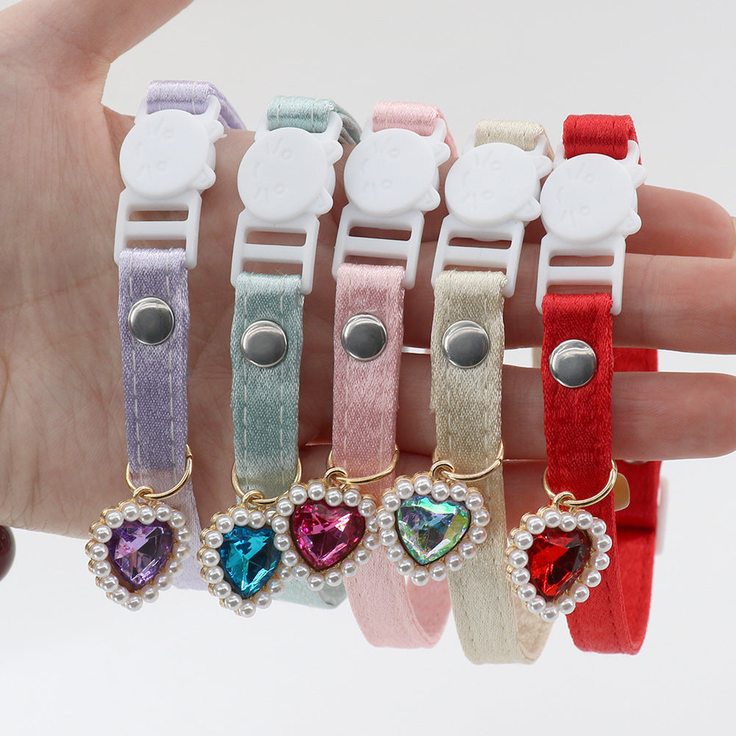 Five colorful cat collars held together to show the buckles, fasteners and heart charms