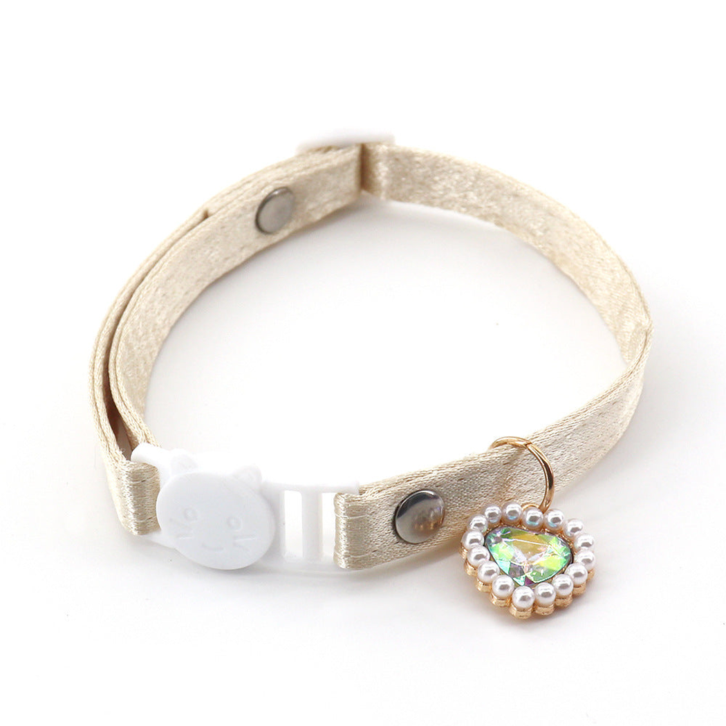 Beige cat collar with a cat-face buckle and iridescent heart charm