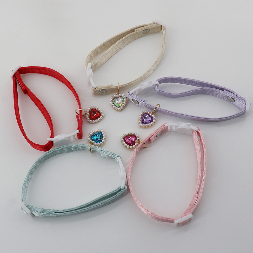 Five colorful cat collars laid open to show their adjustable straps and heart charms