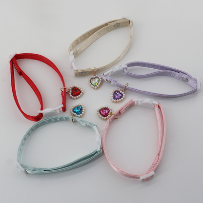 Five colorful cat collars laid open to show their adjustable straps and heart charms