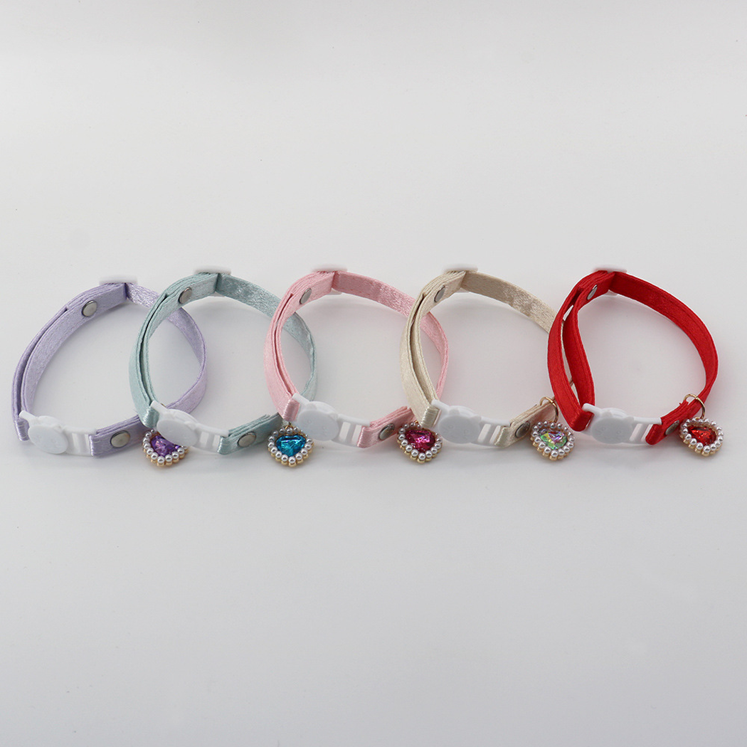 Five colorful cat collars arranged in a row with cat-face buckles and heart charms