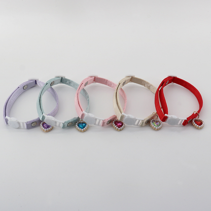Five colorful cat collars arranged in a row with cat-face buckles and heart charms