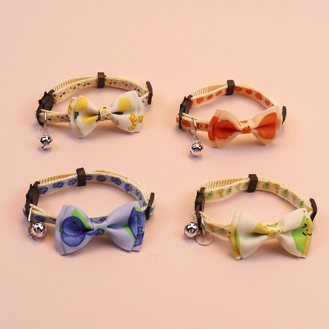 Four fruit-print cat collars displayed with bows and bells