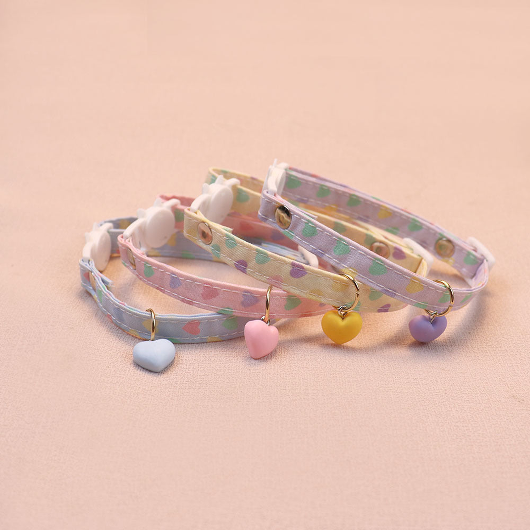 Four pastel heart-print cat collars arranged with their buckles and charms visible