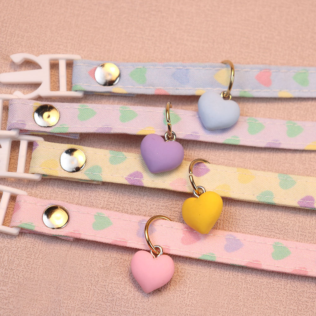 Close-up of heart charms, stitched edges and metal-tone fasteners on four cat collars