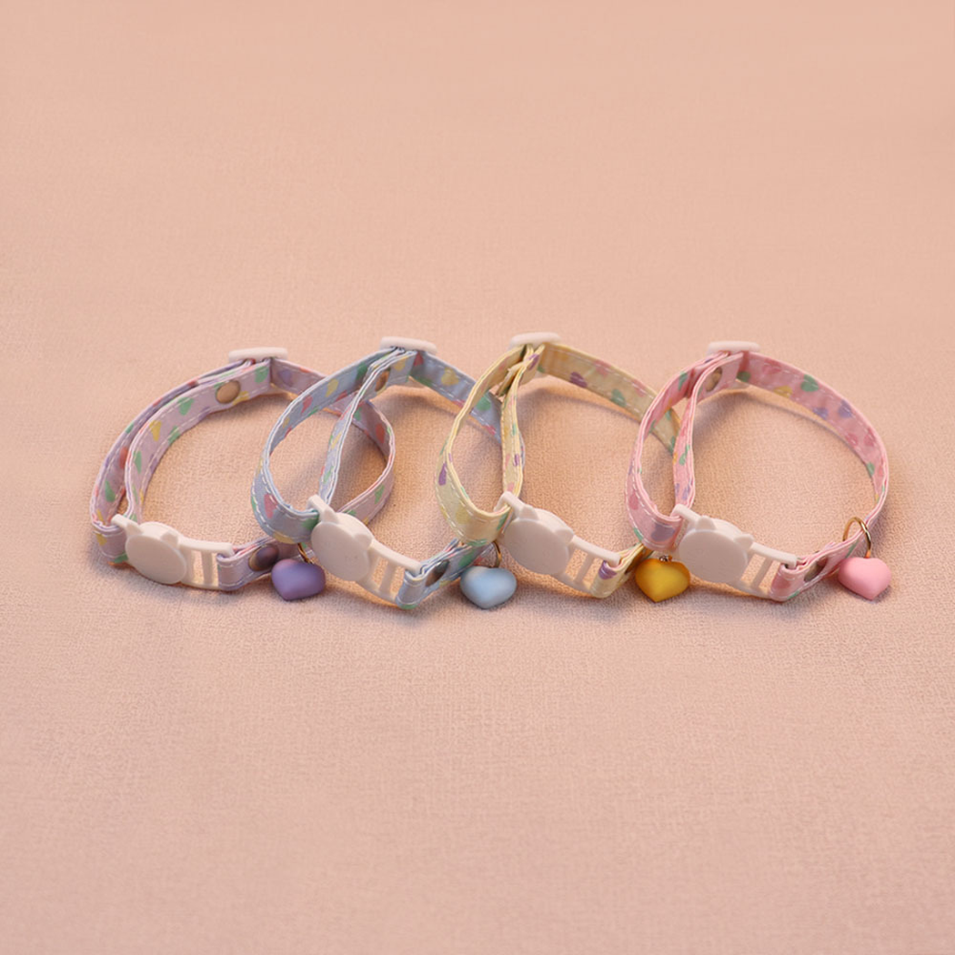 Four pastel heart-print cat collars arranged with their cat-face buckles and charms facing forward