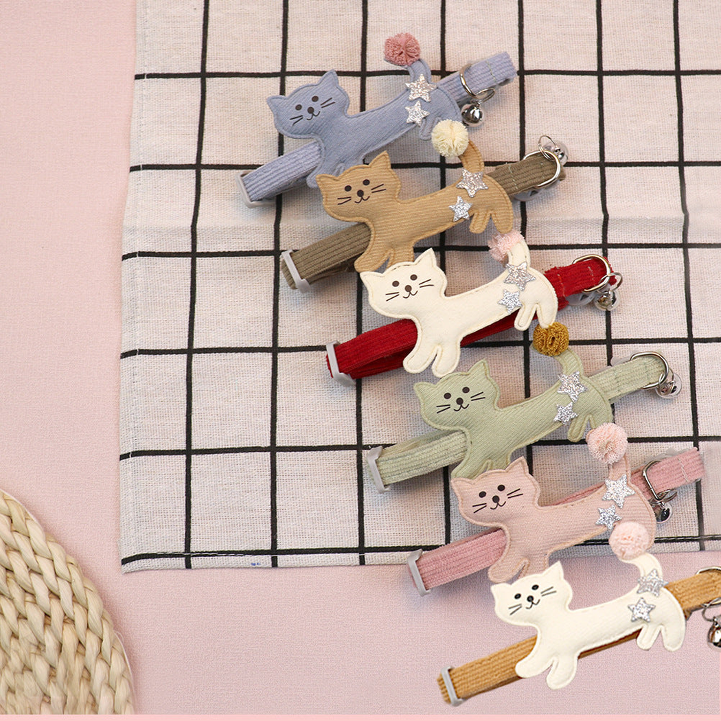 Assorted cat collars arranged on a pink and grid-patterned surface