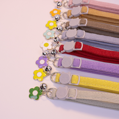 Close-up of colorful collar straps with cat-face buckles, bells and flower charms