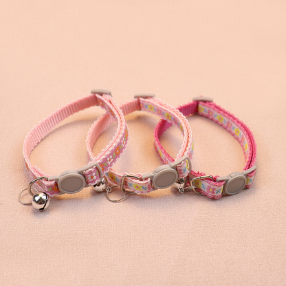 Three pink floral cat collars with bells and round buckles
