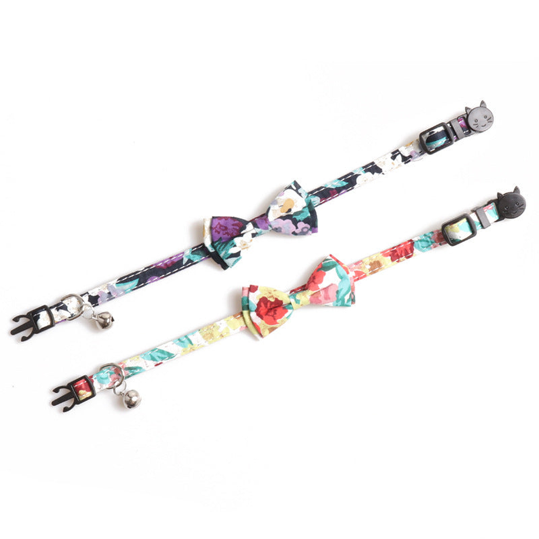 Two floral bow cat collars laid flat to show the straps, buckles and bells