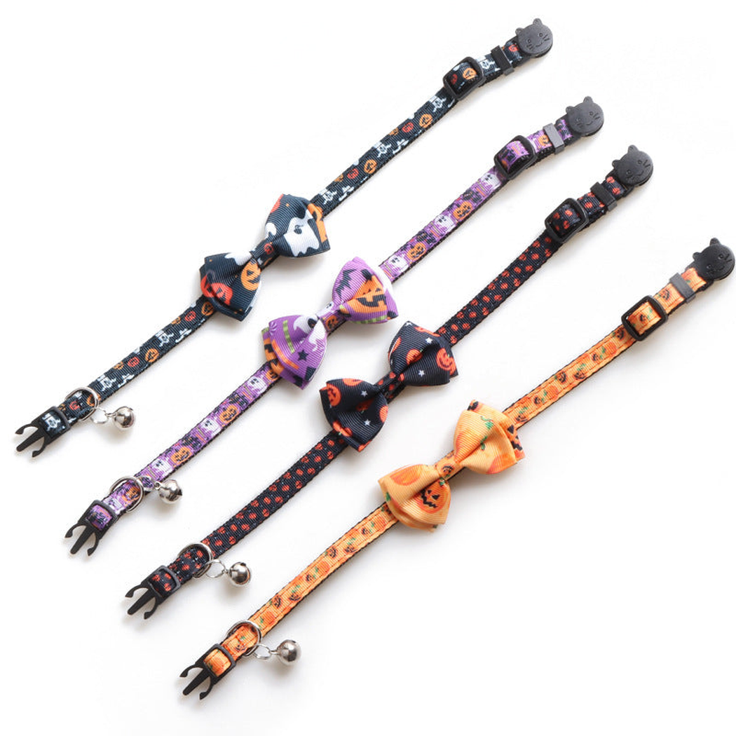 Four pumpkin-print bow cat collars laid flat to show the straps, buckles and bells