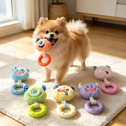 Dog holding the orange monster-face ring toy with other colors arranged nearby