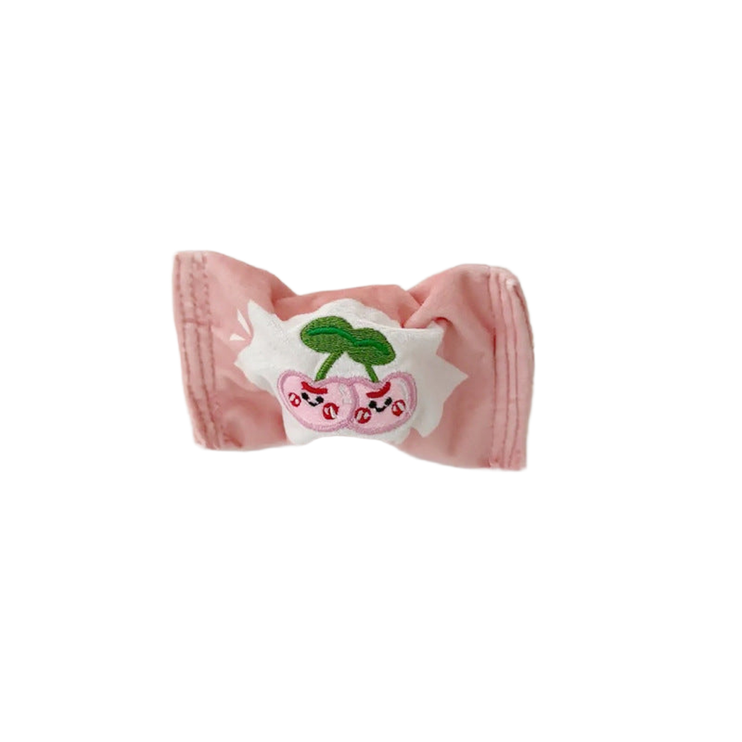 Pink candy-shaped dog toy with cherry face patch, front view
