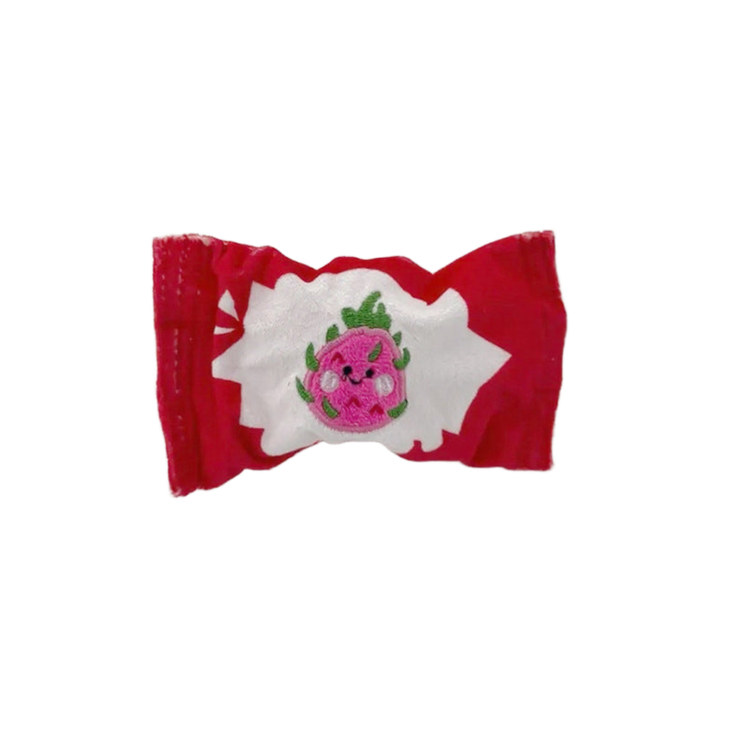 Red candy-shaped dog toy with dragon fruit face patch, front view