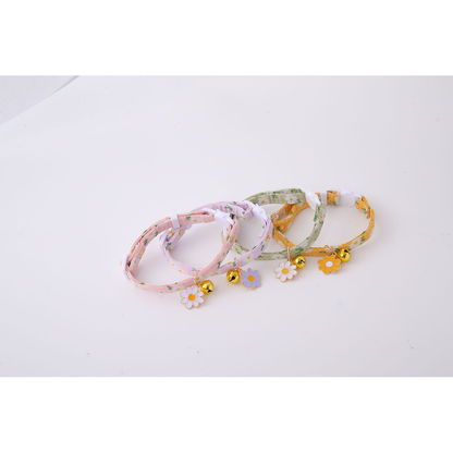 Four daisy-print cat collars arranged in a row with flower charms and bells