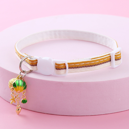 Mustard yellow striped cat collar with white cat-face buckle, bell and shell-themed charms