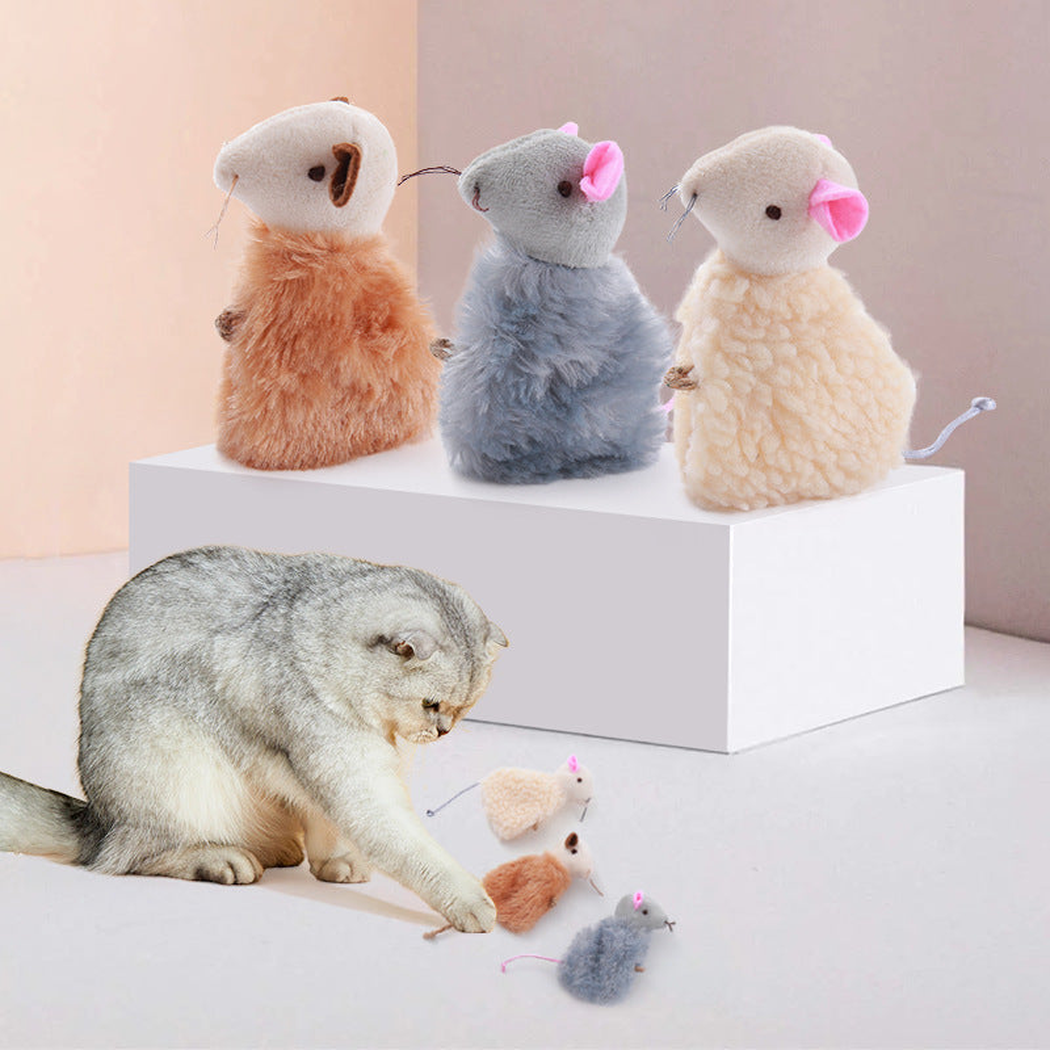 Cat playing beside beige, gray and brown mouse-shaped cat toys