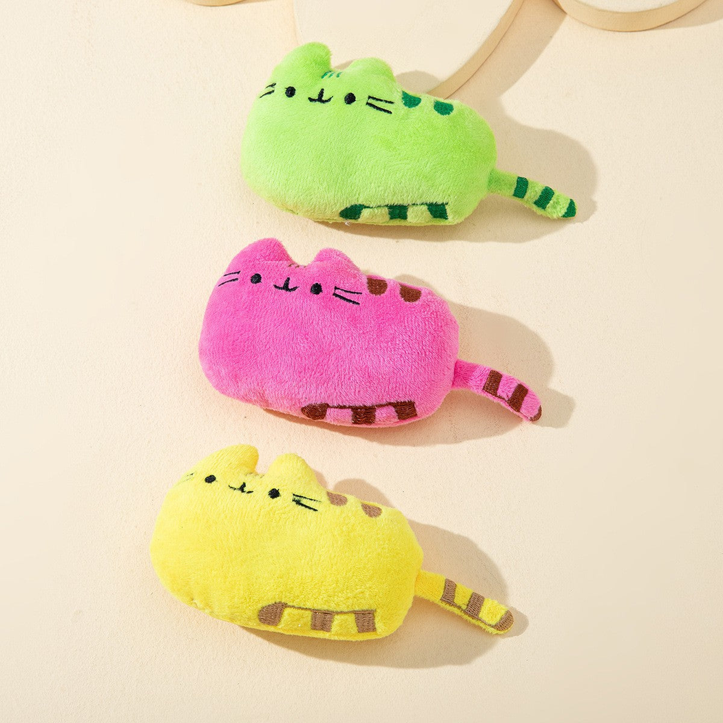 Green, pink and yellow cat-shaped toys arranged on a neutral surface