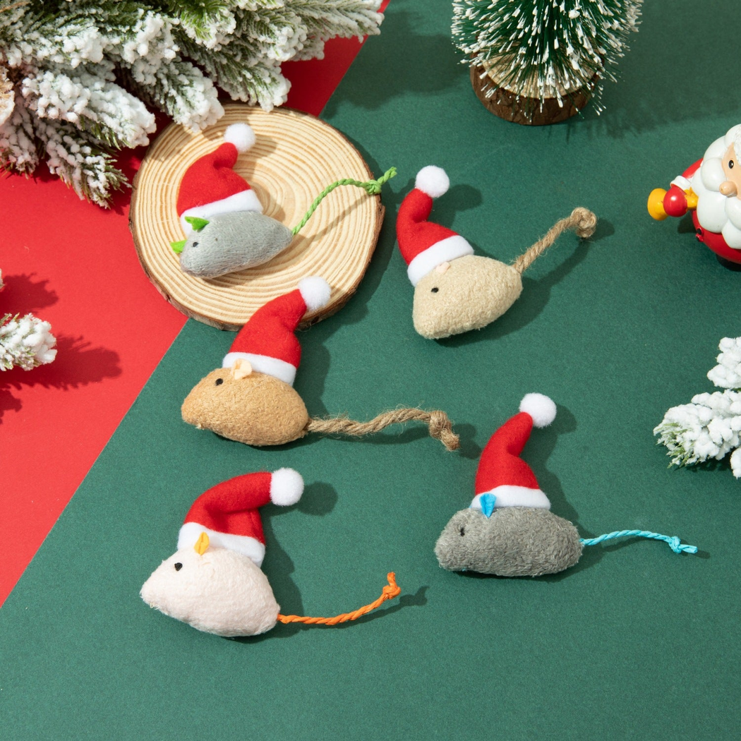 Five mouse-shaped cat toys in Santa hats arranged in a Christmas setting