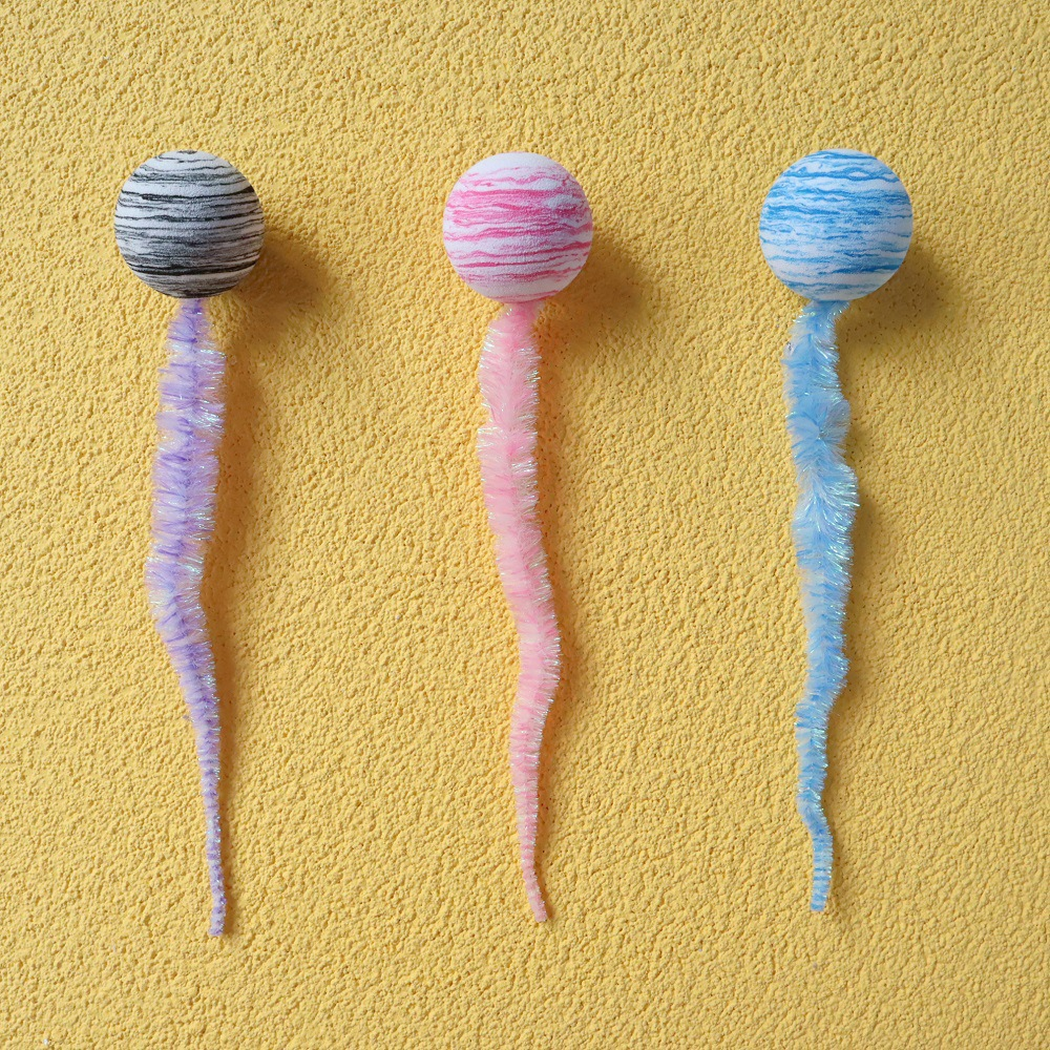Gray, pink, and blue striped ball-and-tail cat toys arranged in a row