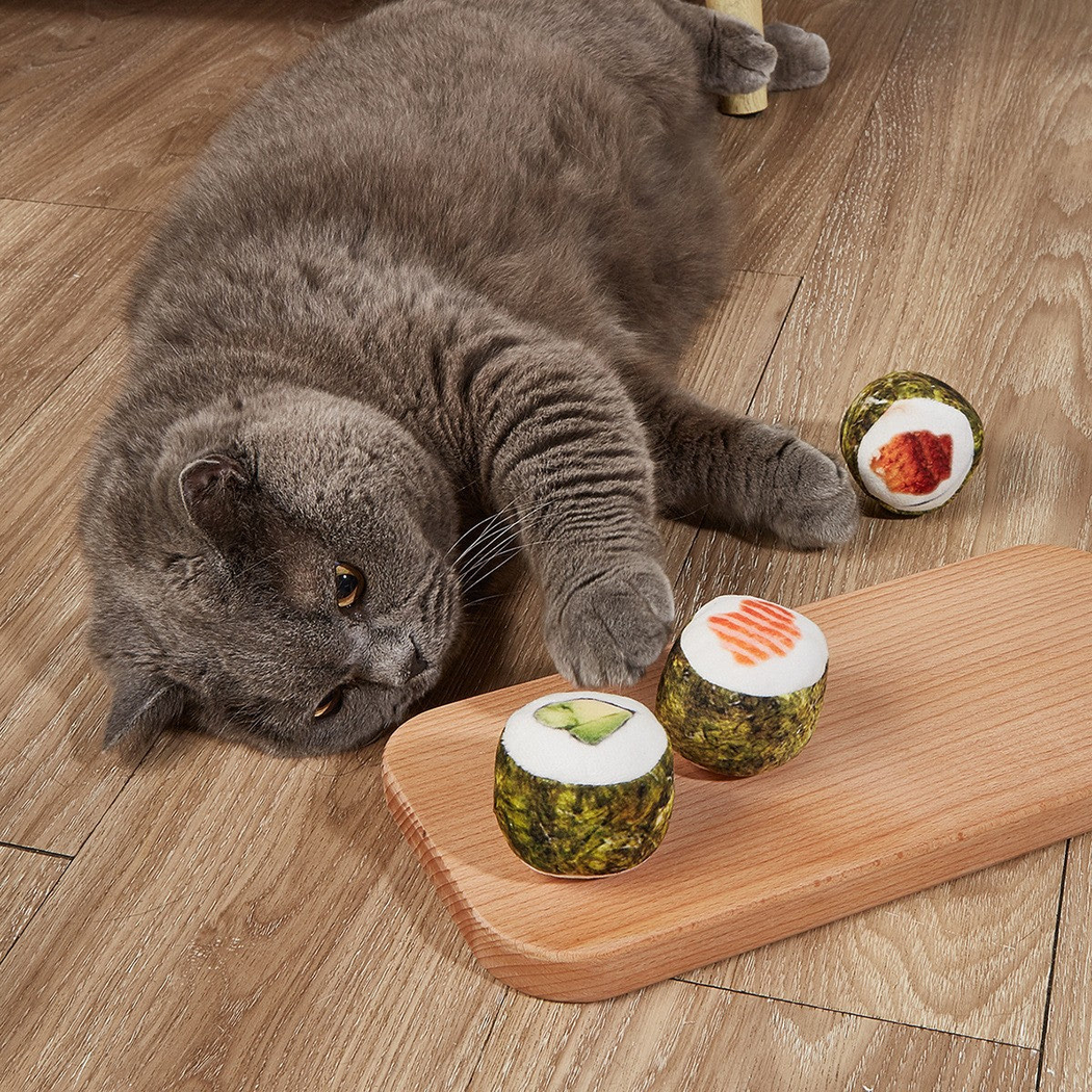 Cat playing beside three sushi roll toys