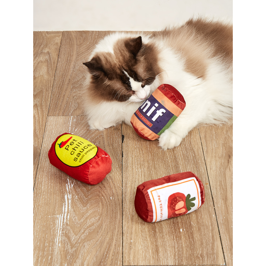 Cat playing with Peanut Butter, Tomato and Chili can-shaped toys