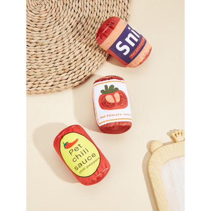 Tomato, Peanut Butter and Chili can-shaped cat toys arranged on a neutral surface
