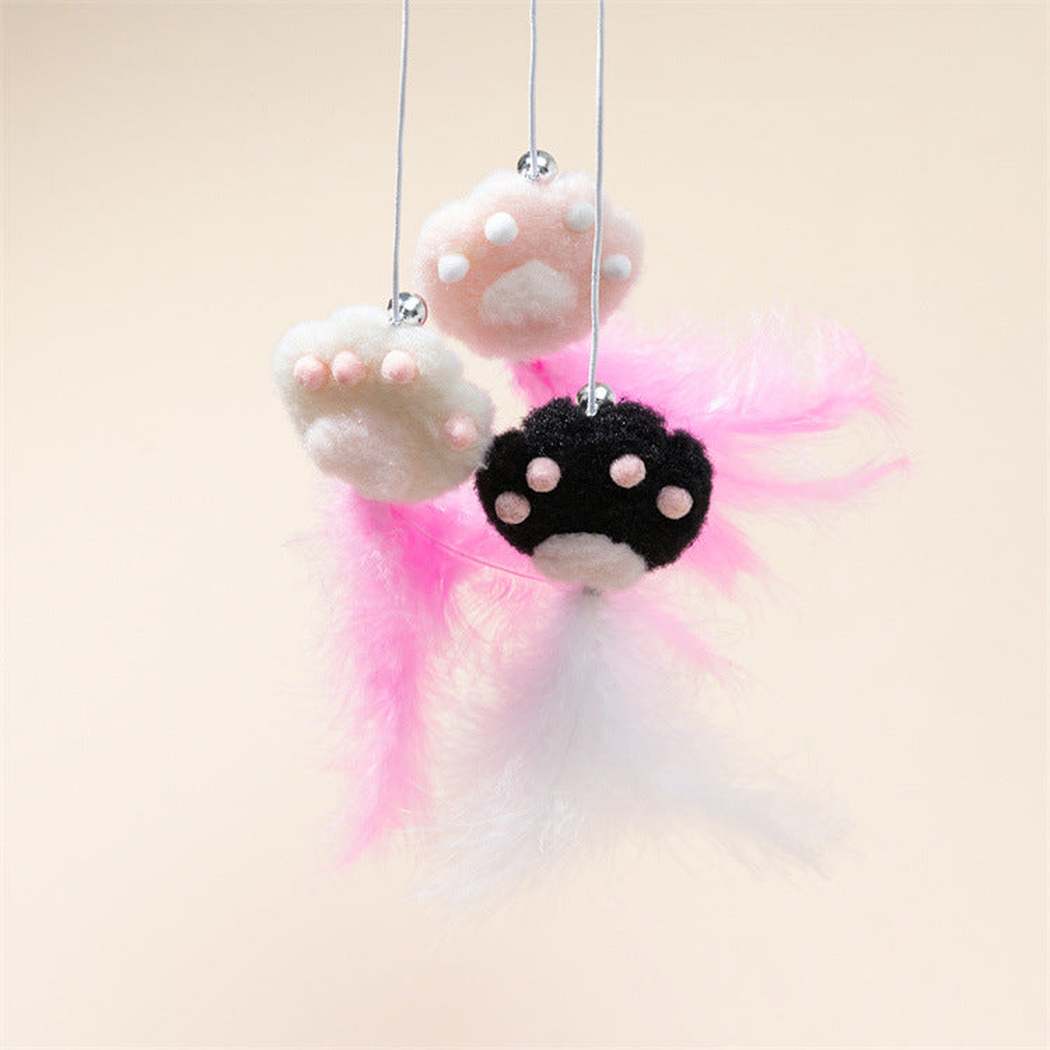 Close-up of pink, white and black paw ornaments with bells and feather tassels