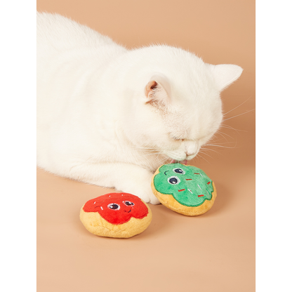 White cat playing with green and red doughnut-shaped toys