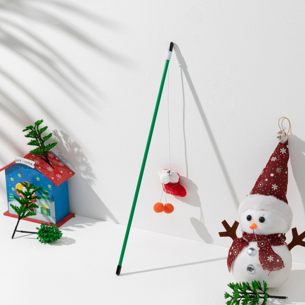 Green cat teaser wand with a red Christmas stocking ornament and orange pom-poms
