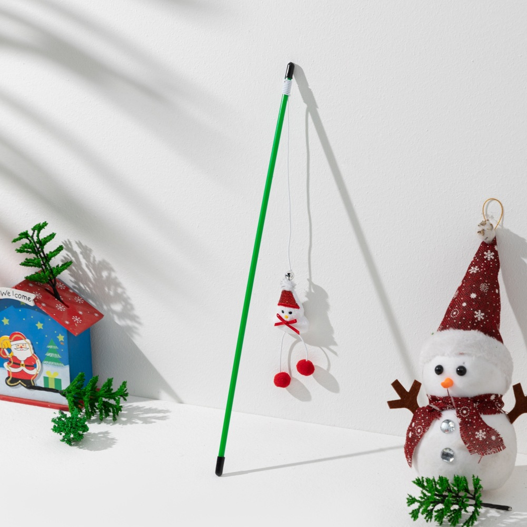 Green cat teaser wand with a snowman ornament and red pom-poms