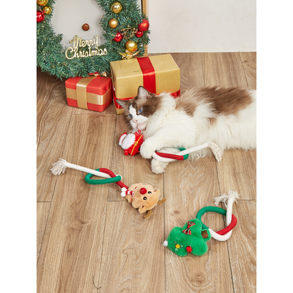 Three holiday rope cat toys arranged beside a cat and Christmas gifts